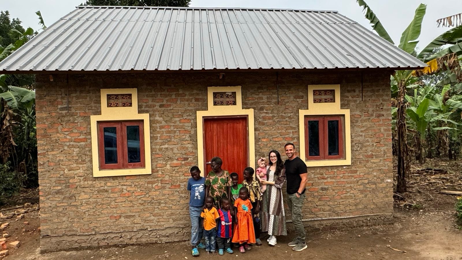 A family in front of the house built for them in Uganda